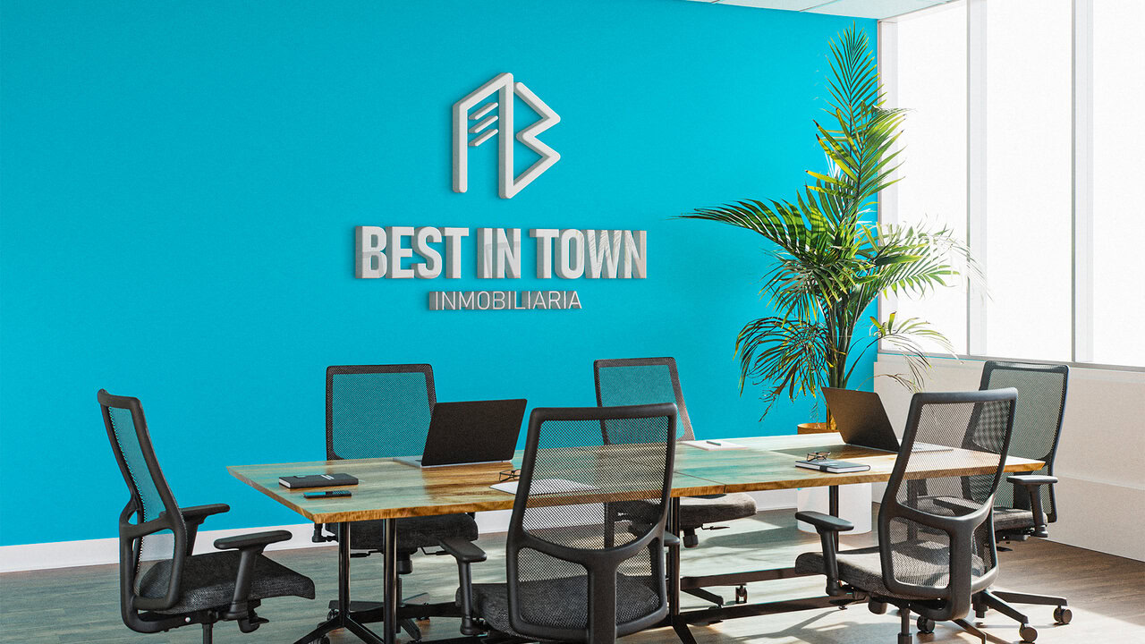 Oficina moderna con pared azul de fondo, en el medio del espacio hay una mesa de madera con sillas de oficina alrededor, ambiente empresarial y juvenil.