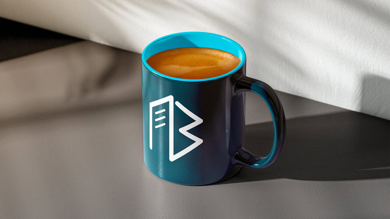 Taza azul turquesa oscuro con el logotipo de una inmobiliaria en la ciudad de puebla, rellena de café.