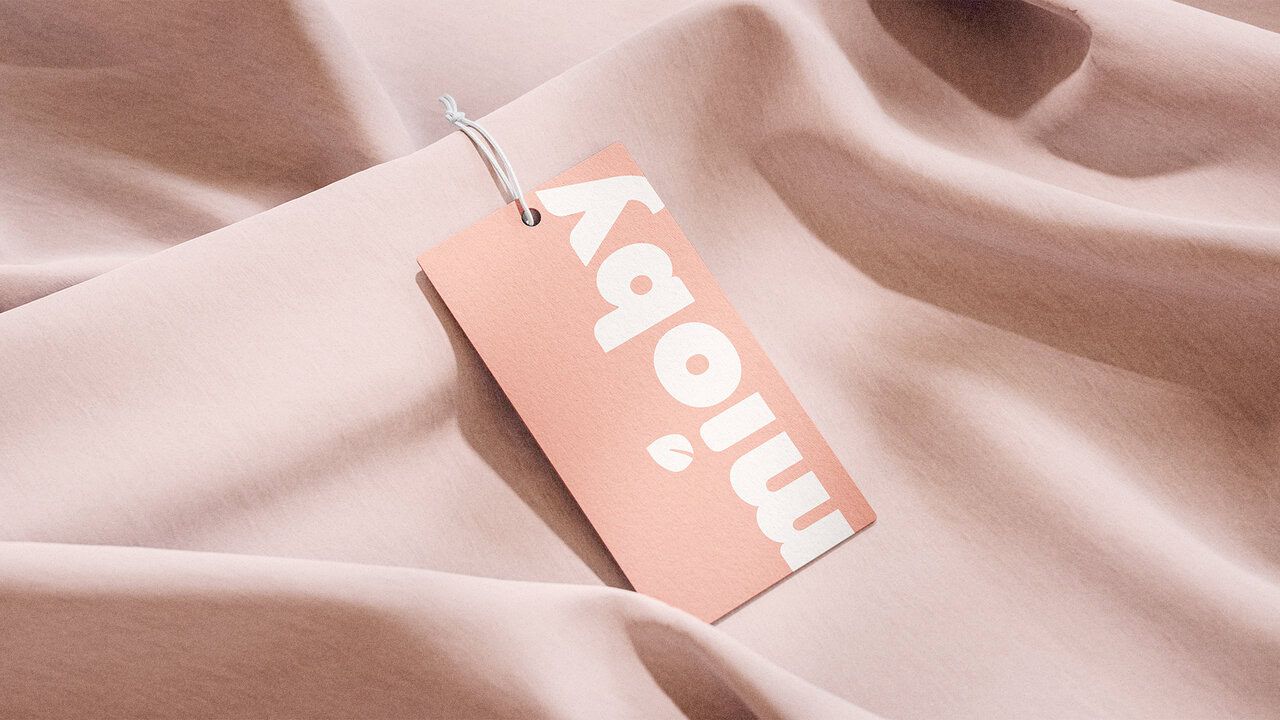 Etiqueta de producto de Mioby. Diseño rectangular en color rosa claro con el logotipo de la marca en blanco. Diseño de etiqueta.